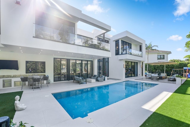 rear view of house with a balcony, an outdoor hangout area, and a patio