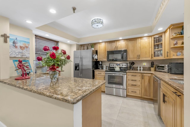 kitchen featuring kitchen peninsula, light stone countertops, ornamental molding, stainless steel appliances, and a raised ceiling