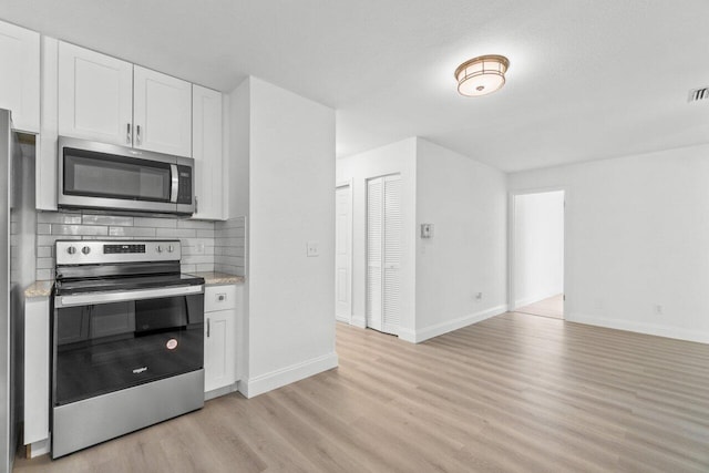 kitchen with decorative backsplash, white cabinets, stainless steel appliances, and light wood-type flooring