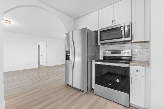 kitchen featuring white cabinets, light hardwood / wood-style flooring, light stone countertops, tasteful backsplash, and stainless steel appliances