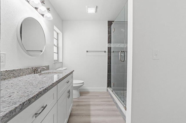 bathroom featuring hardwood / wood-style floors, vanity, a shower with door, and toilet