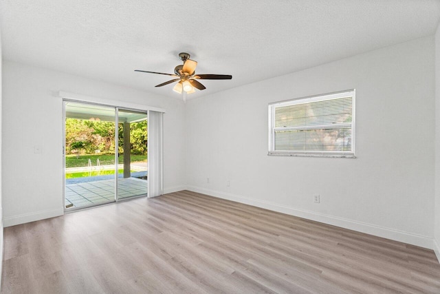 spare room featuring ceiling fan, light wood-type flooring, and a textured ceiling