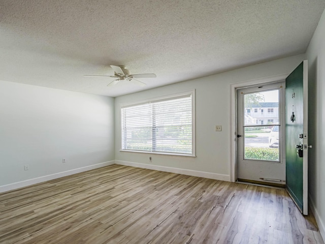 unfurnished room featuring ceiling fan, light hardwood / wood-style flooring, a textured ceiling, and a wealth of natural light