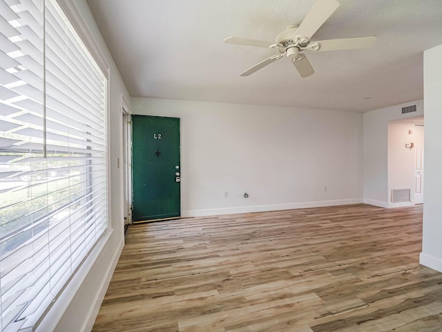 empty room with ceiling fan, a textured ceiling, and light hardwood / wood-style floors