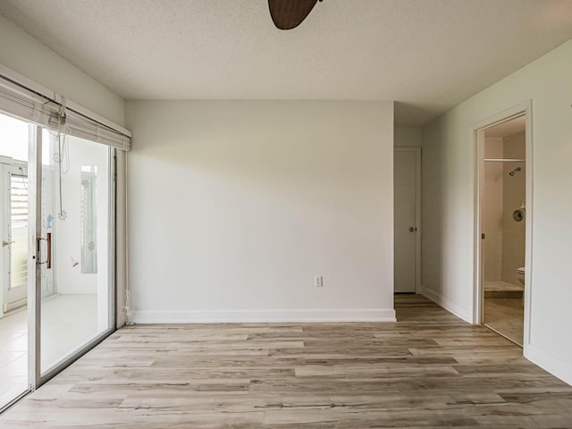 spare room featuring light hardwood / wood-style floors and a textured ceiling