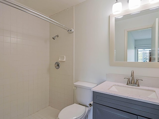 bathroom featuring a tile shower, toilet, and vanity