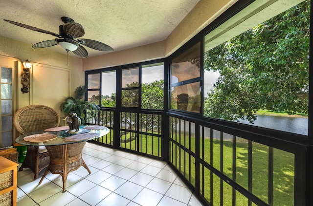 sunroom featuring ceiling fan and a water view