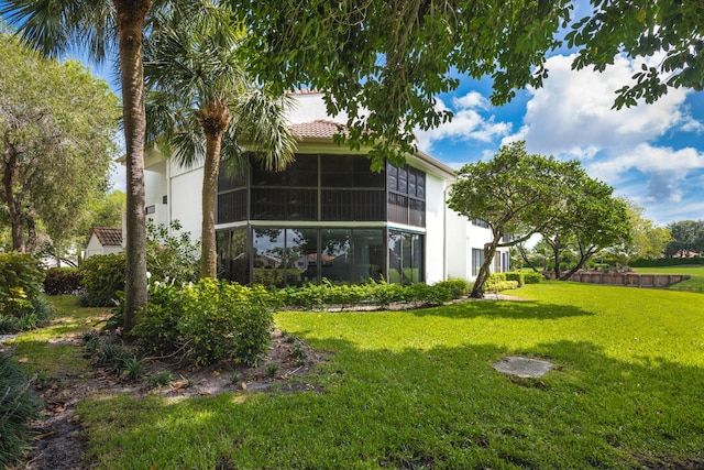 rear view of property featuring a sunroom and a lawn