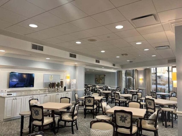 carpeted dining space featuring a drop ceiling