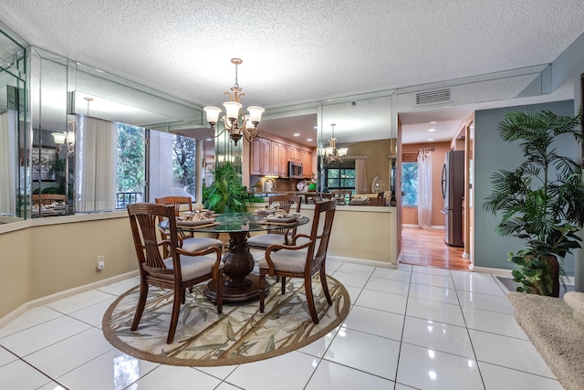 tiled dining area featuring plenty of natural light, a notable chandelier, and a textured ceiling