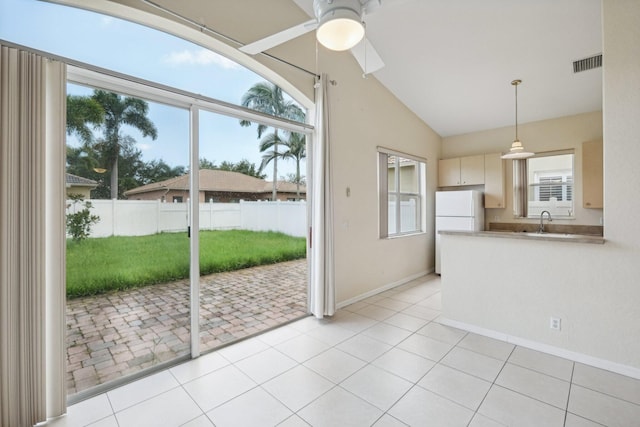 interior space featuring vaulted ceiling, light tile patterned floors, sink, and ceiling fan