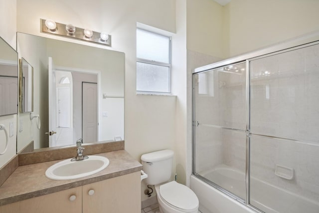 full bathroom featuring vanity, bath / shower combo with glass door, and toilet