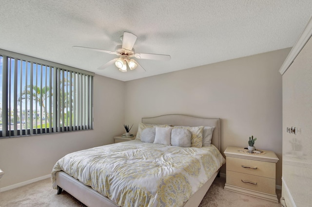 bedroom with ceiling fan, light colored carpet, and a textured ceiling