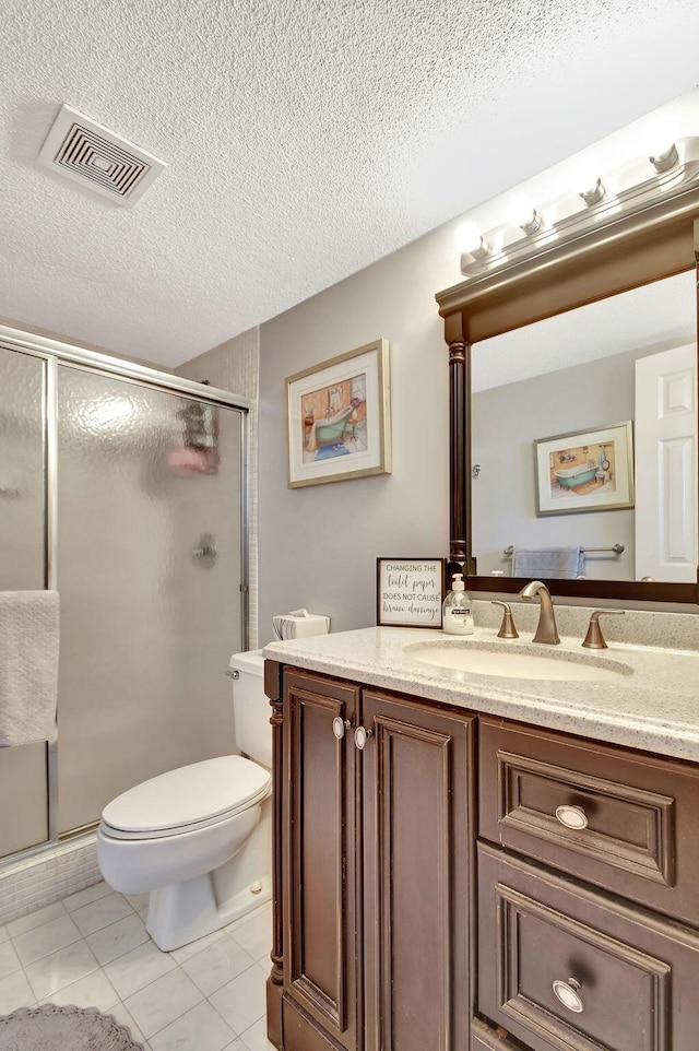 bathroom featuring tile patterned flooring, a textured ceiling, toilet, vanity, and a shower with shower door