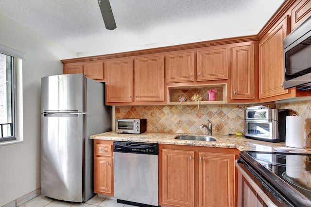 kitchen with light tile patterned floors, a textured ceiling, tasteful backsplash, light stone counters, and stainless steel appliances