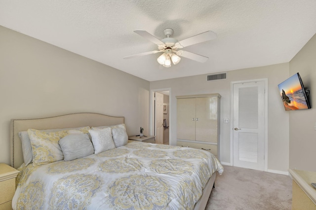 carpeted bedroom with ceiling fan and a textured ceiling