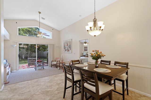 carpeted dining space with ceiling fan with notable chandelier and high vaulted ceiling