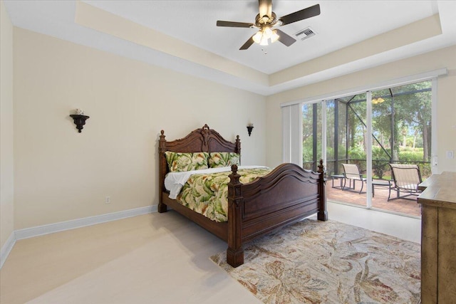 bedroom with access to outside, ceiling fan, and a tray ceiling