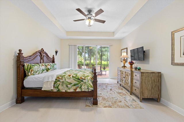 bedroom with access to exterior, a raised ceiling, and ceiling fan