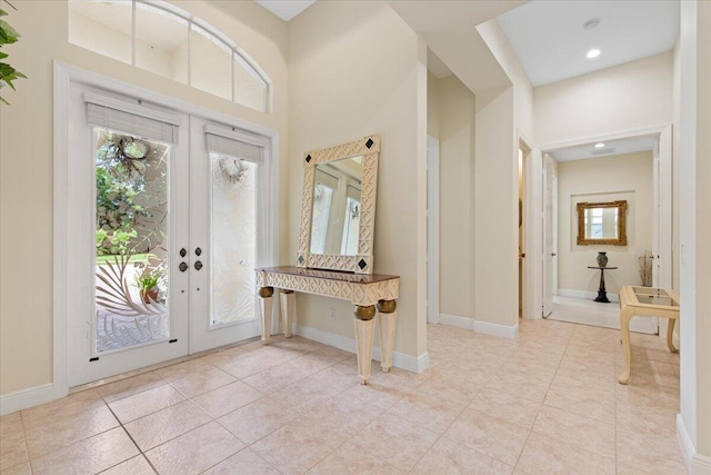 entryway featuring light tile patterned flooring, a towering ceiling, and french doors