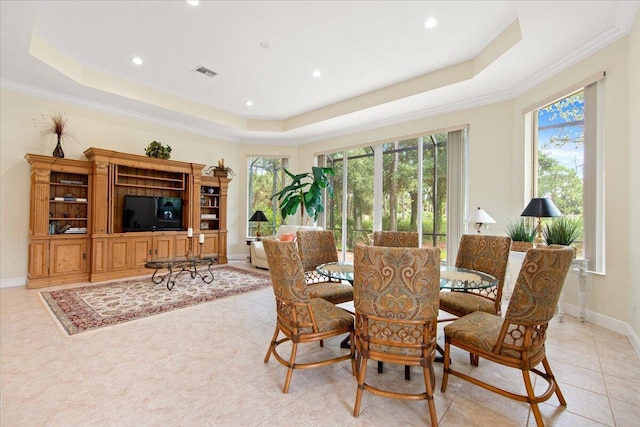 dining room with crown molding, a tray ceiling, and light tile patterned flooring