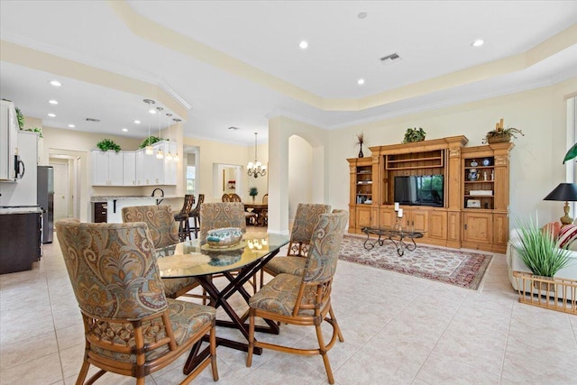 dining area featuring sink, ornamental molding, light tile patterned floors, a notable chandelier, and a tray ceiling