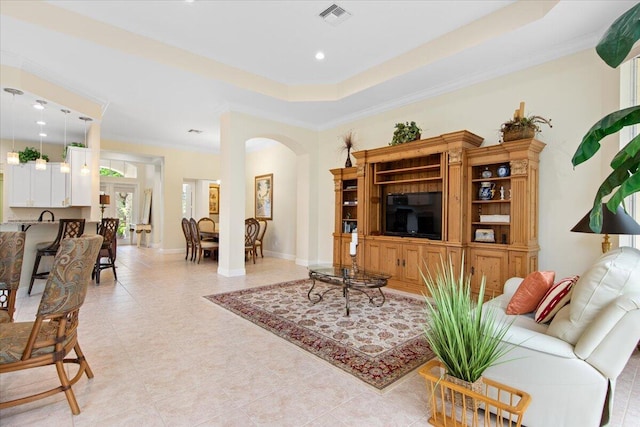 living room featuring a raised ceiling, crown molding, and sink