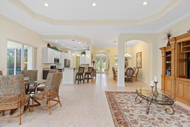 dining room with french doors, ornamental molding, a tray ceiling, and light tile patterned floors