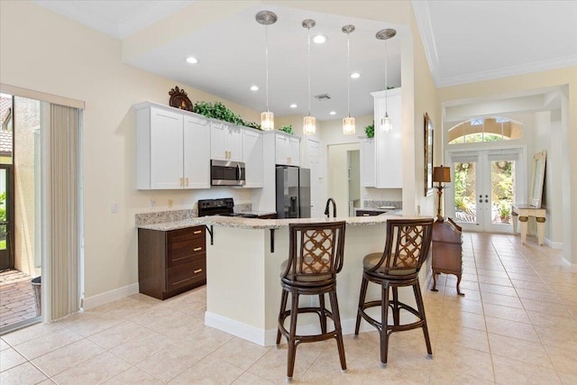 kitchen featuring stainless steel appliances, white cabinetry, a breakfast bar, and light stone counters