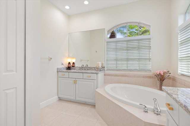 bathroom featuring vanity, a relaxing tiled tub, and tile patterned floors