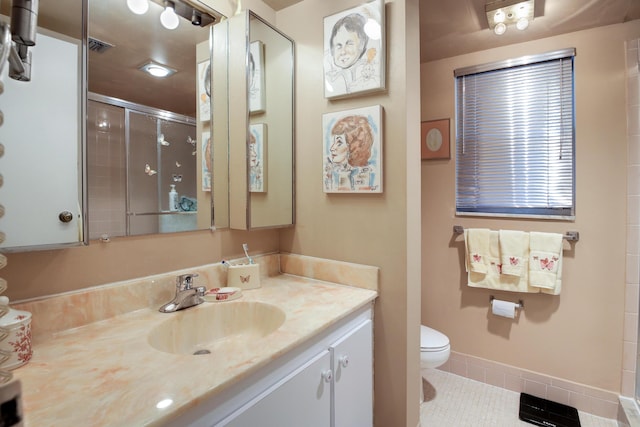 bathroom featuring tile patterned floors, vanity, toilet, and a shower with shower door