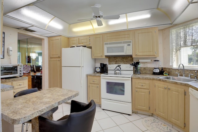 kitchen with white appliances, a kitchen breakfast bar, ceiling fan with notable chandelier, sink, and light tile patterned flooring