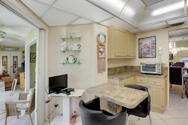 kitchen featuring ceiling fan, light brown cabinets, a breakfast bar area, a paneled ceiling, and light tile patterned floors