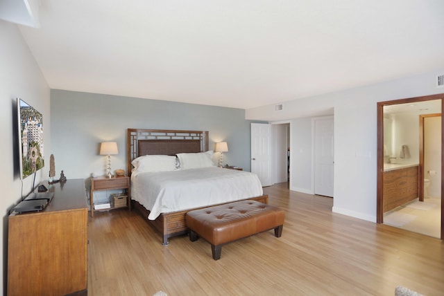 bedroom with light hardwood / wood-style floors and ensuite bath