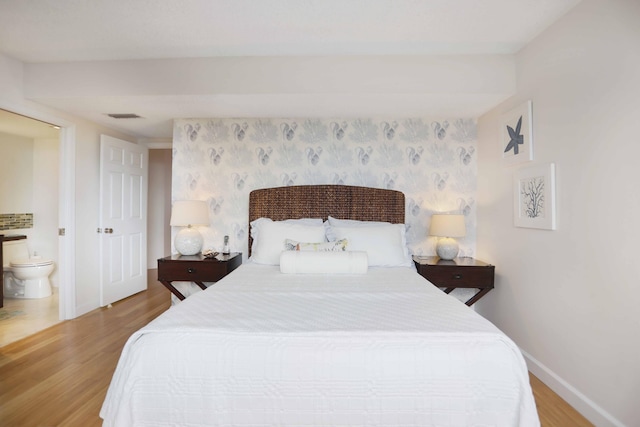 bedroom featuring ensuite bath and light wood-type flooring