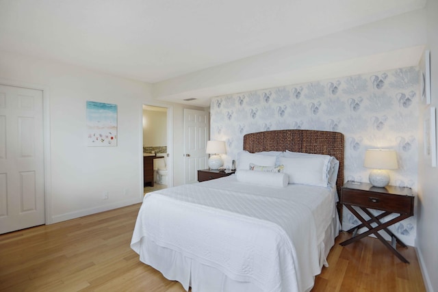 bedroom with hardwood / wood-style floors and connected bathroom