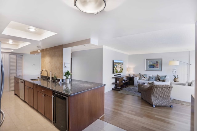 kitchen with sink, beverage cooler, light hardwood / wood-style flooring, stainless steel dishwasher, and dark stone countertops