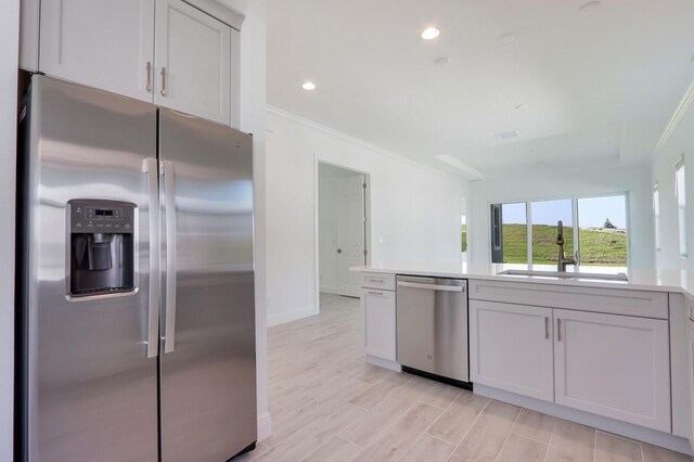 kitchen featuring white cabinetry, ornamental molding, sink, and appliances with stainless steel finishes