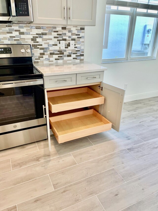 kitchen featuring white cabinets, decorative backsplash, and stainless steel stove