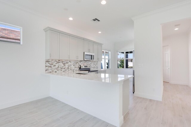 kitchen featuring kitchen peninsula, stainless steel appliances, ornamental molding, and sink