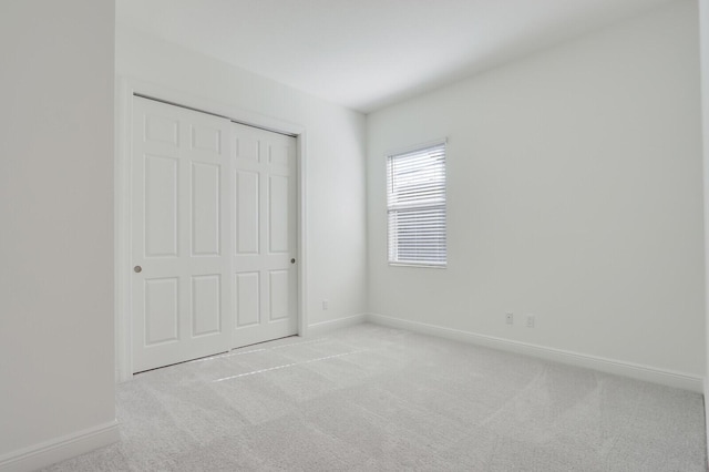 unfurnished bedroom featuring light carpet and a closet