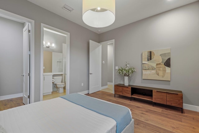 bedroom featuring ensuite bathroom and hardwood / wood-style flooring