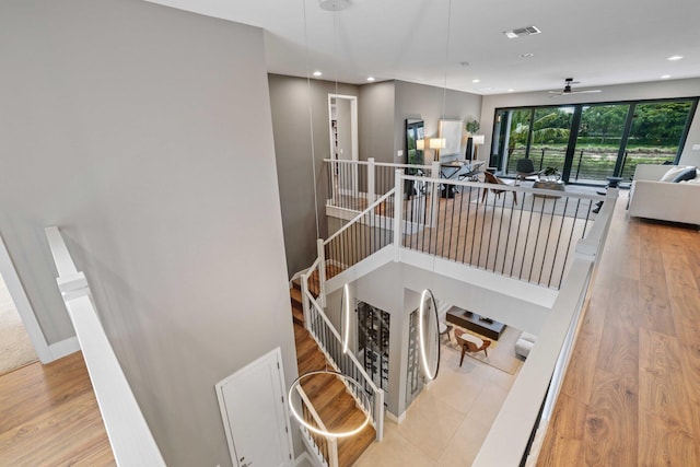 staircase with hardwood / wood-style flooring and ceiling fan