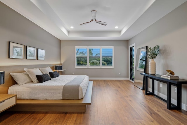 bedroom with wood-type flooring and a tray ceiling