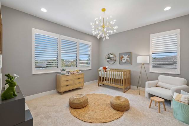 carpeted bedroom featuring a crib and an inviting chandelier