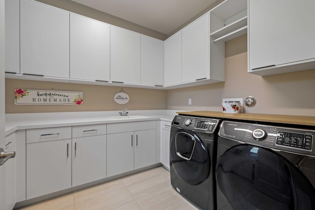 laundry room featuring sink, light tile patterned flooring, cabinets, and independent washer and dryer