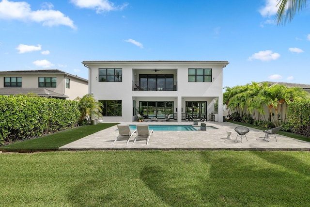 rear view of property featuring a balcony, a patio, ceiling fan, a yard, and a fenced in pool