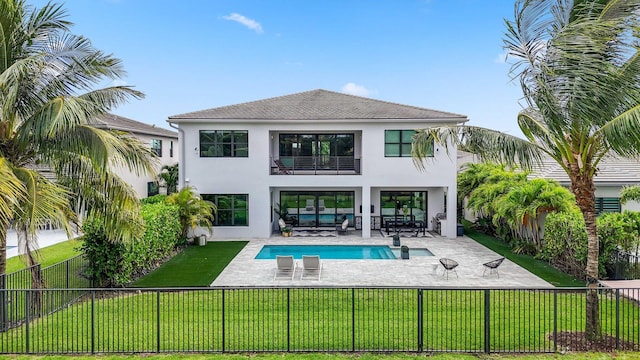 back of property with a fenced in pool, outdoor lounge area, a yard, and a balcony