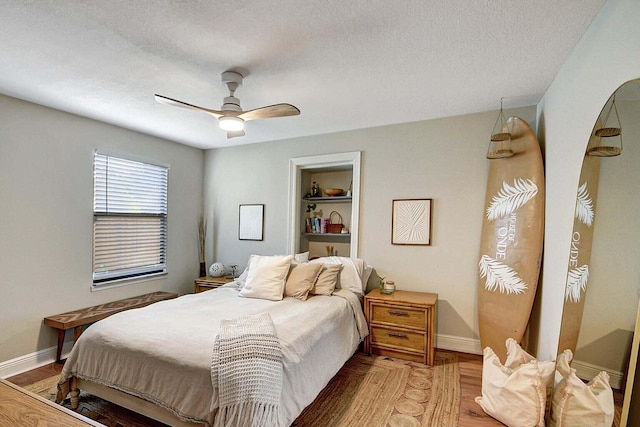 bedroom with ceiling fan, hardwood / wood-style flooring, and a textured ceiling