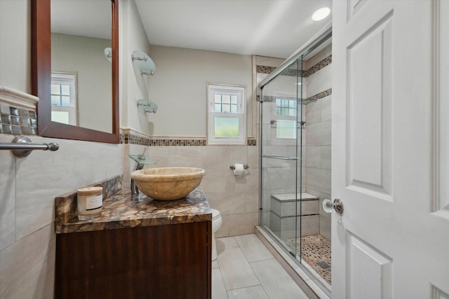 bathroom featuring toilet, an enclosed shower, tile walls, vanity, and tile patterned flooring